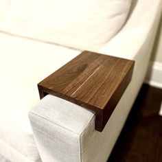 a close up of a white couch with a wooden table in the corner on it