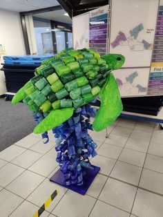 a sculpture made out of green and blue plastic bottles in an office cubicle area