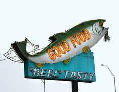 a large fish sign hanging from the side of a building