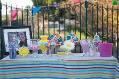 a table topped with candy and lollipops next to a fence