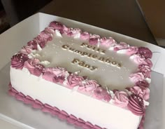 a white and pink cake sitting on top of a table