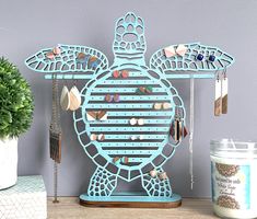 a blue sea turtle shaped jewelry holder on a shelf next to a potted plant