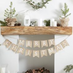 a mantel decorated for christmas with pine cones, candles and garland on it's mantle