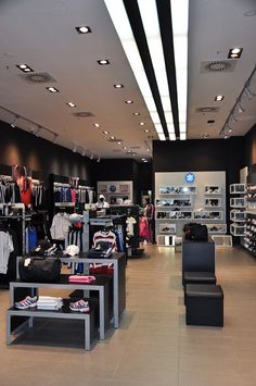 the inside of a clothing store with lots of clothes and shoes on display in it