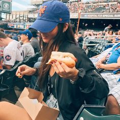 a woman eating a hot dog at a baseball game