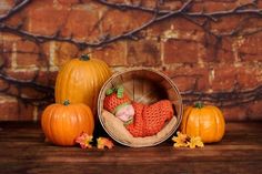 a baby is sleeping in a basket surrounded by pumpkins and other autumn decorations on a wooden table