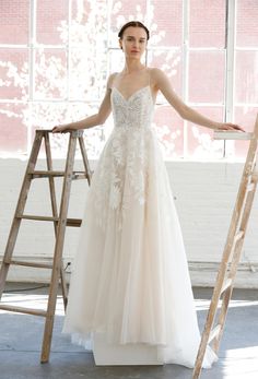 a woman in a wedding dress standing next to a ladder