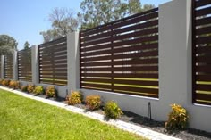 a fence that is made out of wood and concrete with plants growing on the side