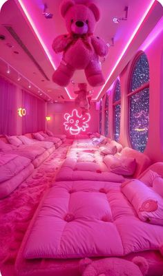 there is a pink room with lots of pillows and a teddy bear hanging from the ceiling