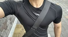 a man taking a selfie with his camera strap attached to his chest and wearing a black shirt