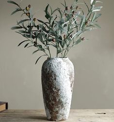 a vase filled with green plants on top of a wooden table