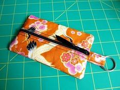 an orange flowered purse sitting on top of a green cutting board