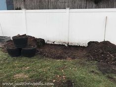 three buckets are sitting in the dirt near a white fence and some green grass