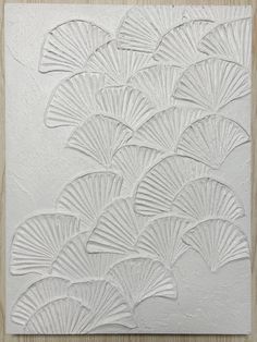 an art work with white paint and paper fan shapes on the wall in front of it