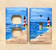 two light switch plates with lighthouses painted on them sitting next to each other in front of the ocean