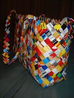 a multicolored woven bag sitting on top of a black cloth covered tablecloth