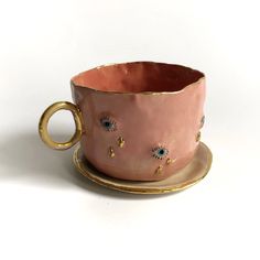 a pink cup and saucer with gold rim