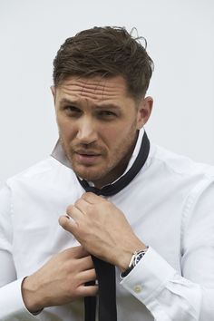 a black and white photo of a man adjusting his tie