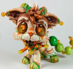 a cat figurine sitting on top of a table next to green balls and beads