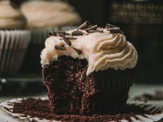 a chocolate cupcake with white frosting and sprinkles on a plate