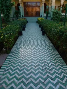 the walkway is lined with potted plants in front of an entrance to a building