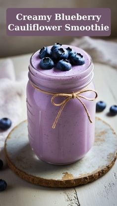 blueberry cauliflower smoothie in a mason jar on a coaster with the words creamy blueberry cauliflower smoothie