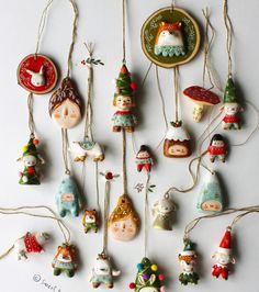 a collection of christmas ornaments hanging from strings on a white surface with an ornament in the middle