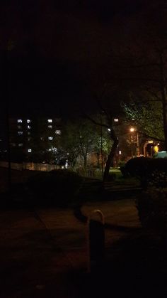 a dark street at night with trees and buildings in the background