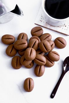 some cookies are on a white table next to a cup of coffee and a spoon