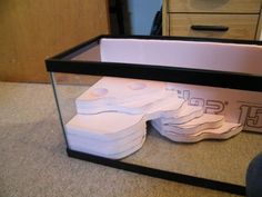 several pieces of white paper are in a glass case on the floor next to a drawer