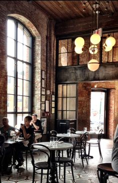 people sitting at tables in a restaurant with large windows