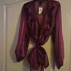 This Blouse Has Never Been Worn. The Material Is A Very Vibrant Burgundy/Plum Color That Is Sheer. It Also Has A Slight Sparkle To The Material. It Wraps Around The Waist And Has A Ruffle Down The Front. It Would Be Perfect For The Holiday Parties Coming Up With A Nice Pair Of Dress Pants Or Skirt. Or Very Cute With A Pair Of Jeans And Some Boots. Ashley Stewart, Plum Color, Beautiful Blouses, Holiday Parties, Dress Pants, The Holiday, Plum, Top Blouse, Sparkle