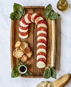 sliced tomatoes, mozzarella and basil on a wooden platter with garlic bread