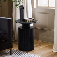 a black table with a vase on it in front of a window