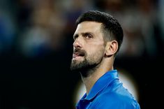 a male tennis player in a blue shirt is looking to the side with his eyes closed