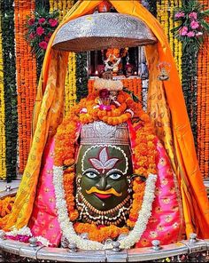 an idol is sitting in the middle of a stage with flowers and garlands around it