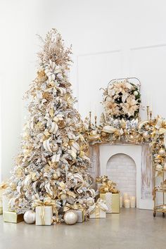 a decorated christmas tree in front of a fireplace with gold and silver decorations on it