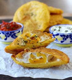 some fried food is on a plate with dipping sauces and other foods in bowls