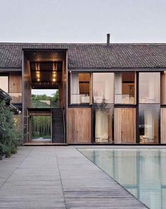 an outdoor swimming pool in front of a large building with wooden doors and windows on each side