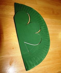 a green paper plate with a leaf cut out on it sitting on a wooden table