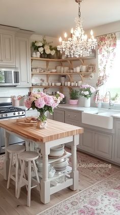 a kitchen with white cabinets and pink flowers in vases on the island counter top