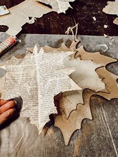 someone is making a leaf out of old newspaper and glues it on the table