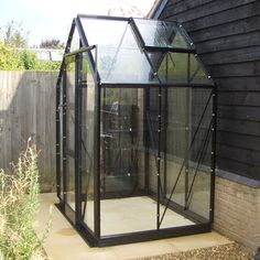 a small black greenhouse in the middle of a yard