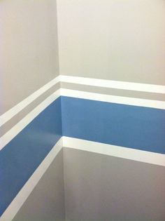 the corner of a bathroom painted in blue and grey stripes on the wall with a toilet