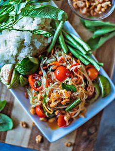 a white plate topped with veggies and rice next to another plate of food