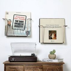 an old record player sitting on top of a wooden dresser next to two books and a potted plant