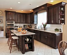 a large kitchen with wooden cabinets and marble counter tops, along with white tile flooring