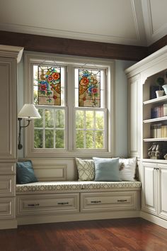 a window seat in the corner of a room with bookshelves and cabinets on either side