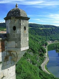 an old tower on top of a hill overlooking a river