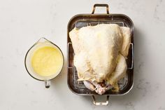 a chicken in a pan next to a glass of orange juice